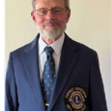 Man in a navy blazer with a Lions Club patch.