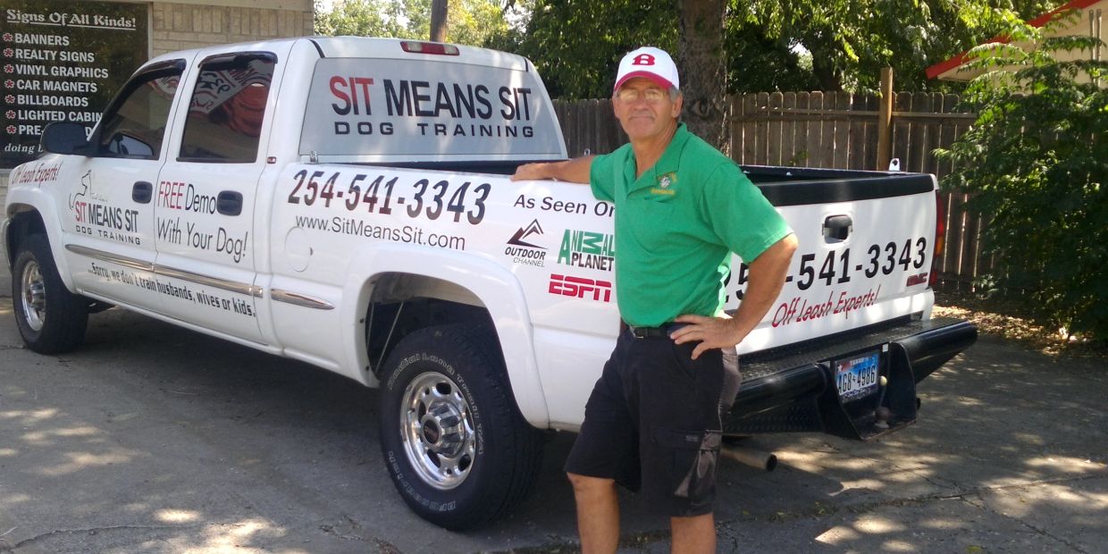 Man in green shirt stands next to dog training truck.