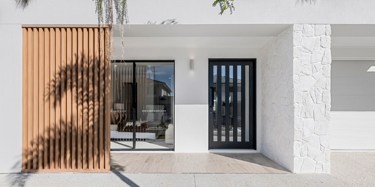 Modern house entrance with black vertical door and wood paneling.
