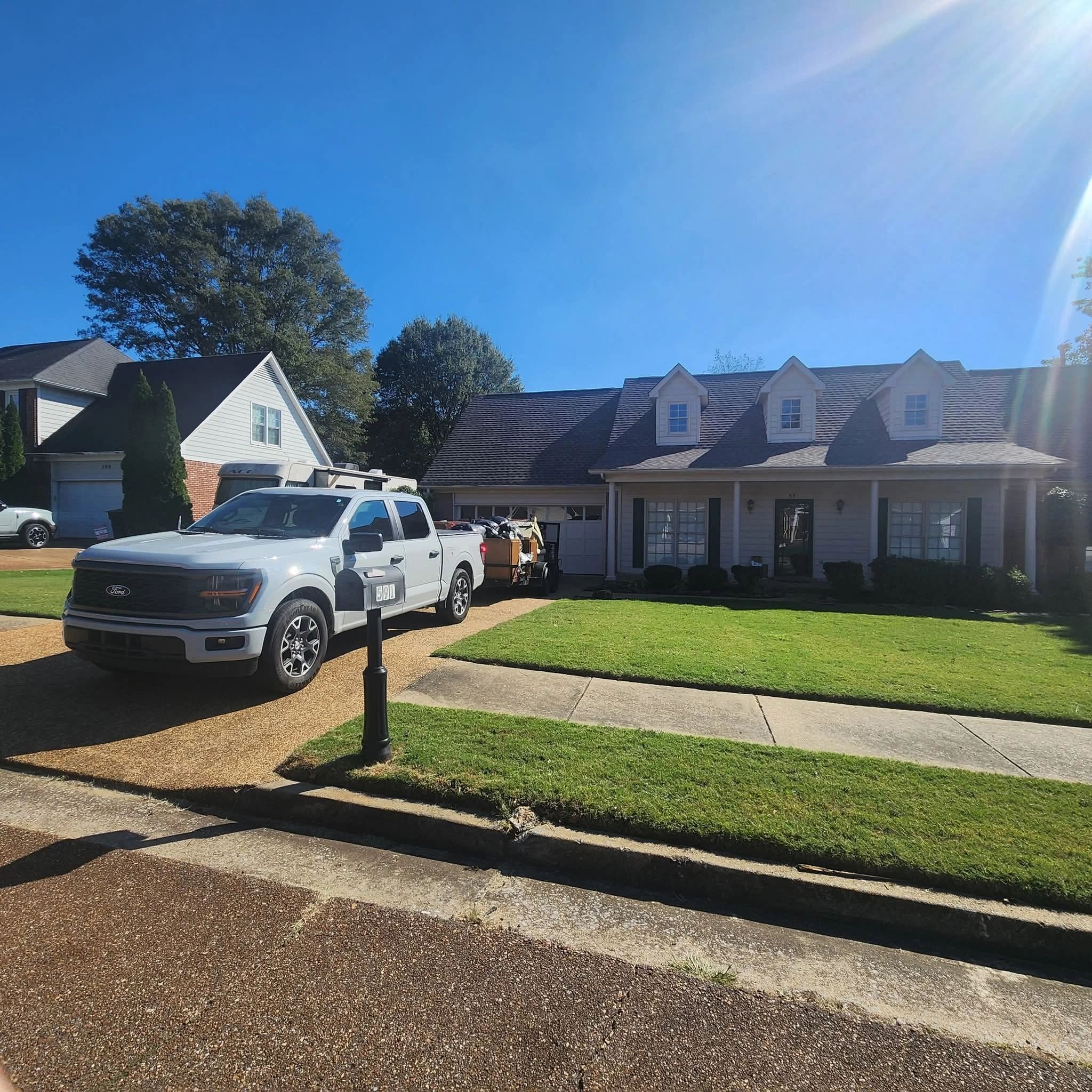 Suburban houses with a white truck and trailer parked outside on a sunny day.