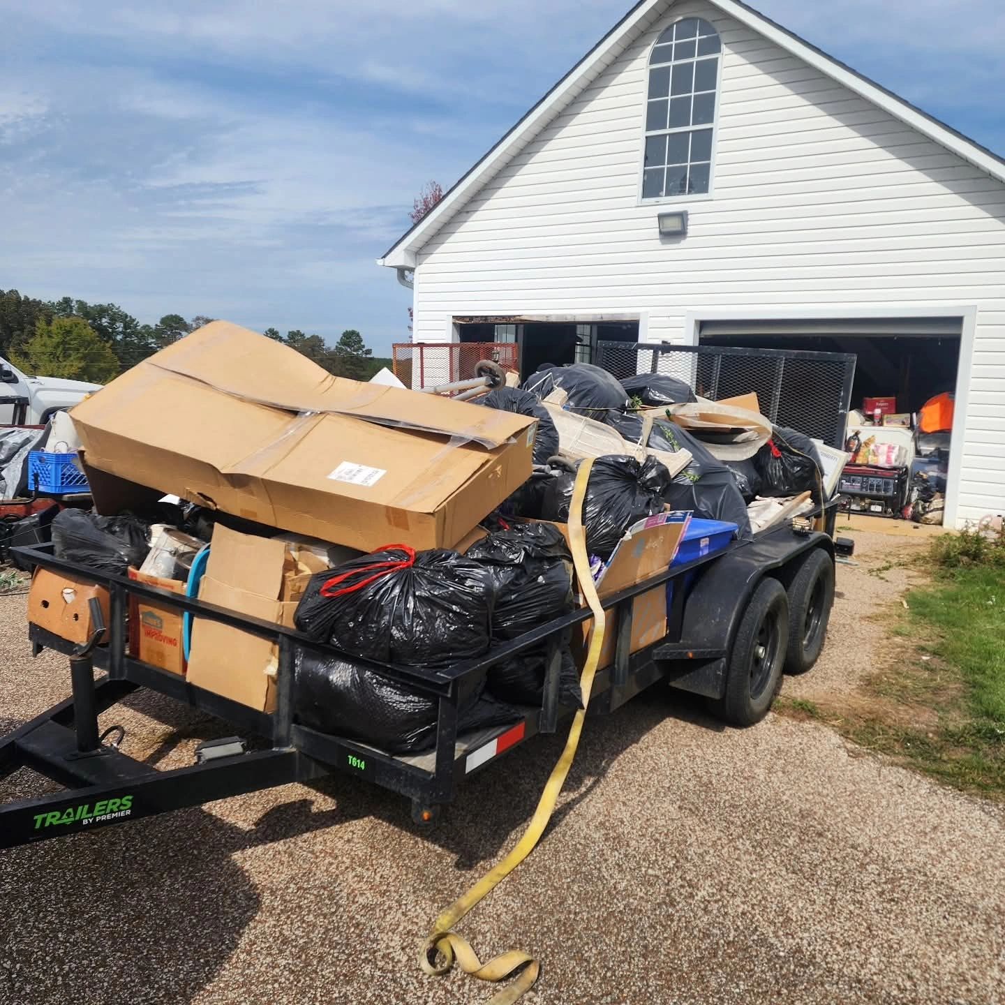 Trash-filled trailer parked outside a white house.