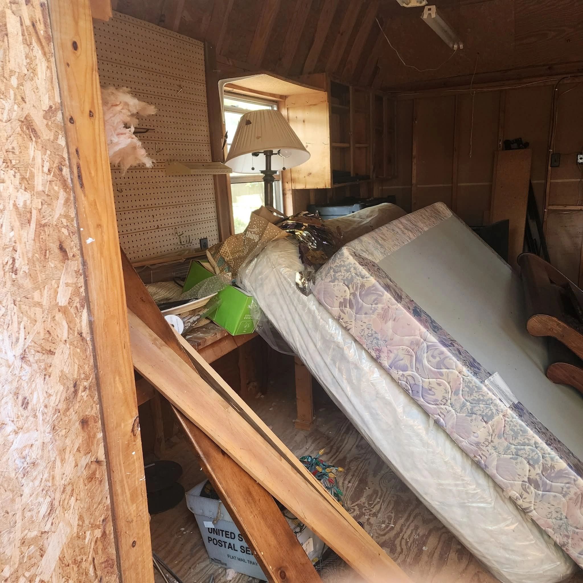 Cluttered storage space with mattresses and wooden beams.