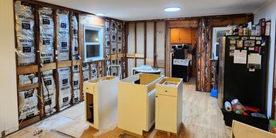 Kitchen under renovation with exposed insulation and cabinets.