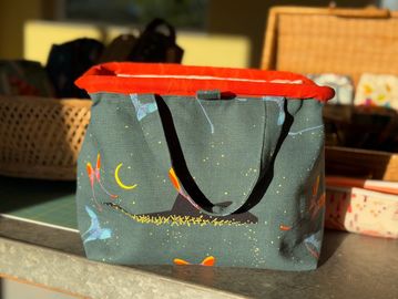 Colorful fabric bag with black handles and celestial pattern on a countertop.