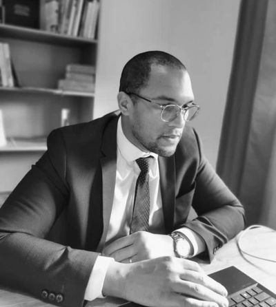 A man in a suit working on a laptop at a desk.