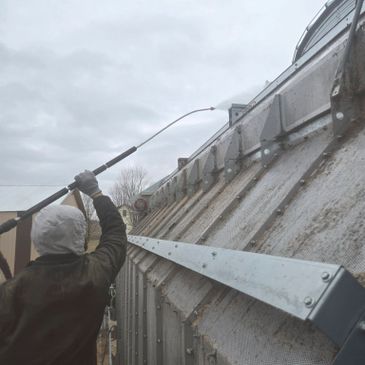 Person power washing a large metal structure outdoors.