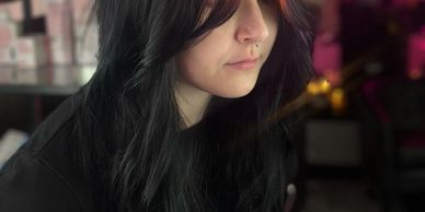 Pensive young woman with dark hair in low light.
