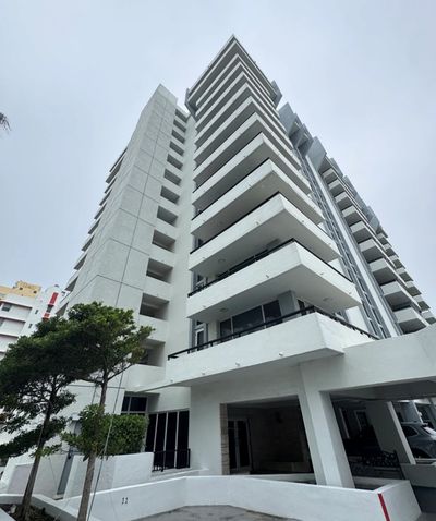 Modern white apartment building with balconies against a cloudy sky.