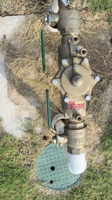 Outdoor water valve system with green covers on grass.