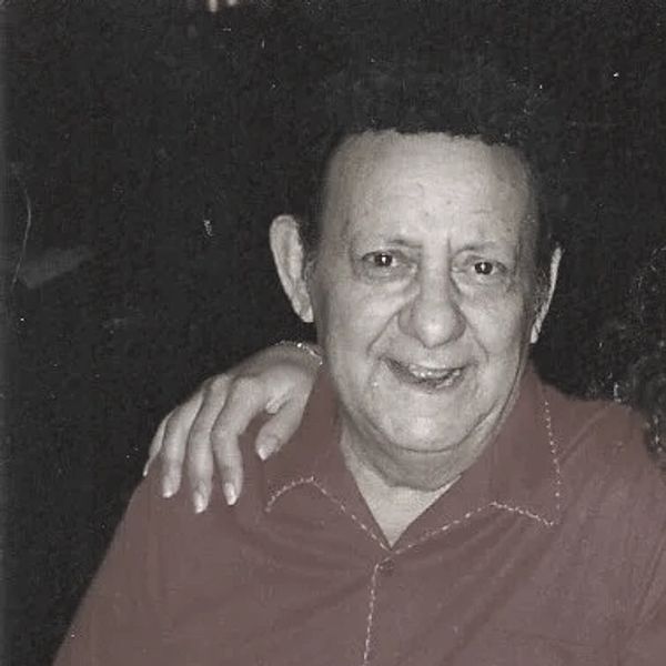 Smiling elderly man with an arm around him.
