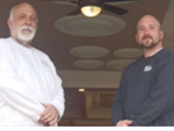 Two men standing indoors facing the camera.