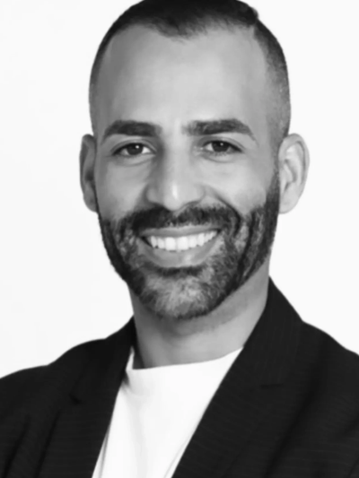 Smiling man with a beard in a black jacket and white shirt.