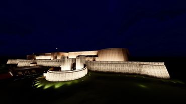 Illuminated fortress at night, showcasing its imposing walls and structures against a dark sky.