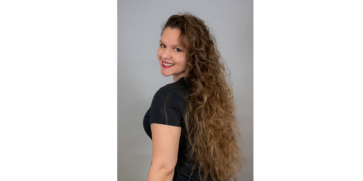 Smiling woman with long curly hair wearing a black shirt.