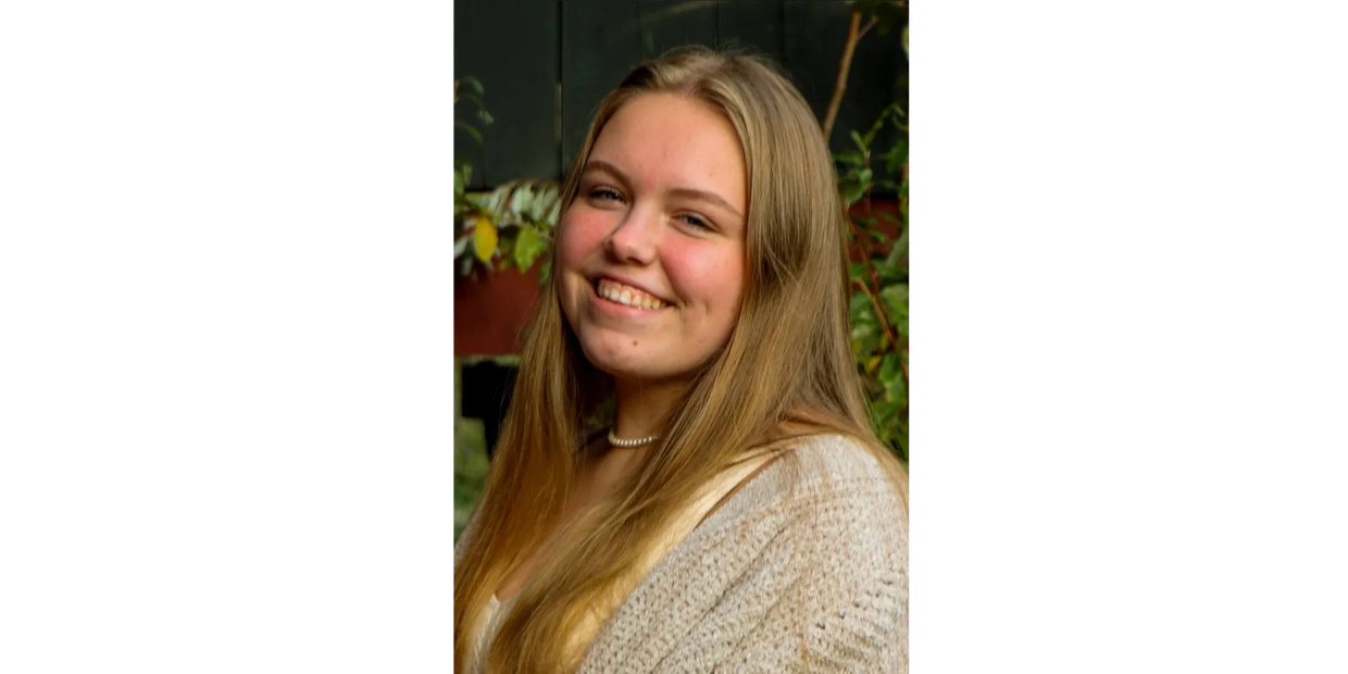 Smiling young woman with long blonde hair outdoors.