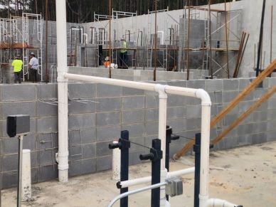 Construction site with workers and plumbing pipes.