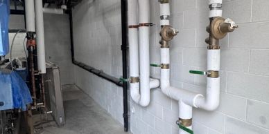 A clean utility room with pipes along a white wall.