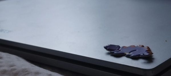 A small, dark purple object rests on the corner of a closed laptop.