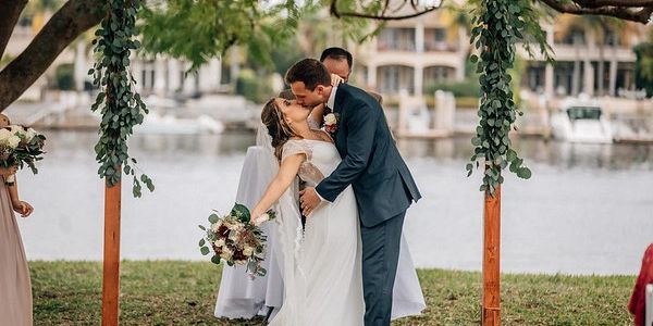 Bride and groom kissing at outdoor waterfront wedding ceremony.