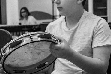 Black & white photo of a student practicing the Brazilian pandiero at drum camp.