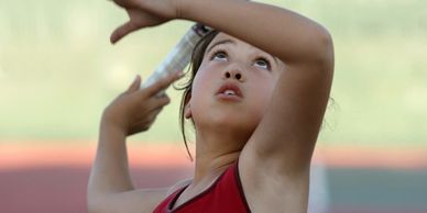 Young girl preparing to throw a javelin during a sports event.