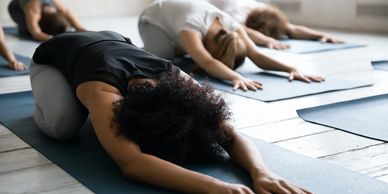 Group practicing yoga in child's pose on mats indoors.