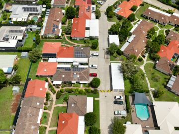 Aerial view of a residential neighborhood with cars and a swimming pool.