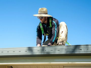 Man working on roof in safety harness.