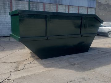 Large green dumpster on cracked pavement.