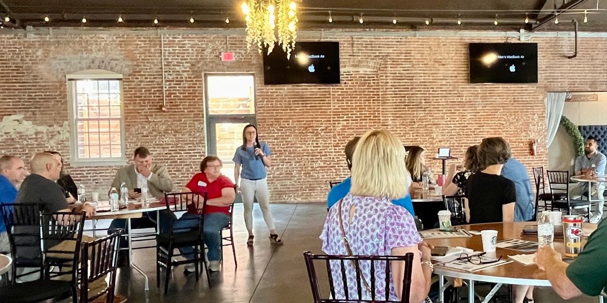 People attending a presentation in a rustic brick-walled room.