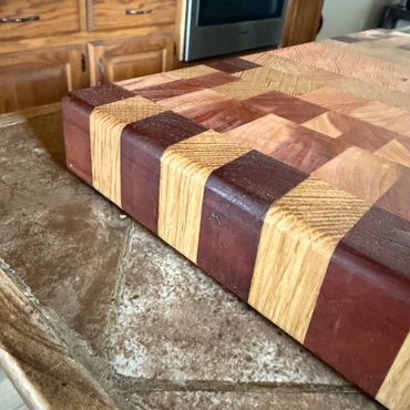 Close-up of a wooden cutting board with alternating light and dark wood blocks.