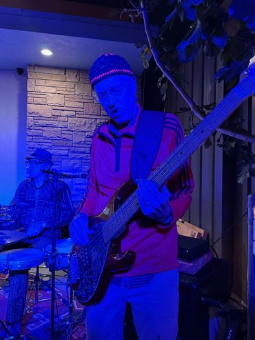 Musician playing bass guitar under blue stage lighting at a live performance.