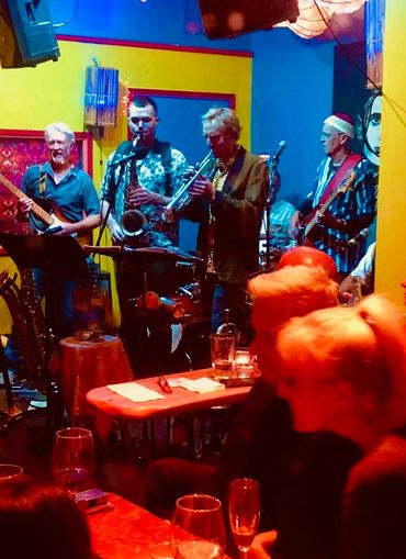 A jazz band performs live in a vibrant, colorful club setting.