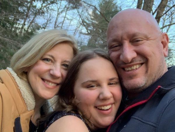 Drs. Tracy and Barney Fritz smiling outdoors with their daughter, Louisa.