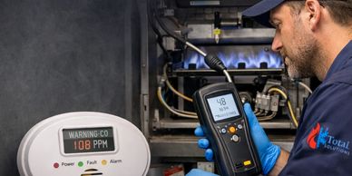 Technician testing for carbon monoxide leaks using specialized equipment near a furnace.