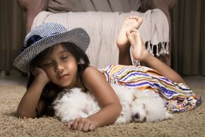 Little girl and puppy sleeping on clean carpet