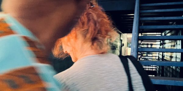 Blurred image of two people walking by a blue staircase.