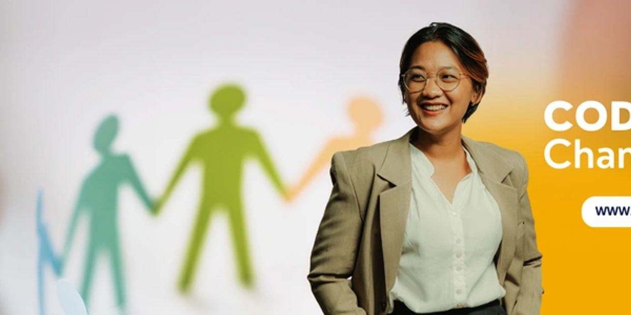 Smiling professional standing next to colorful paper chain figures promoting CODIGGO Champs.