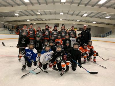 Hockey instructor posing with group of participants of fundraiser camp.