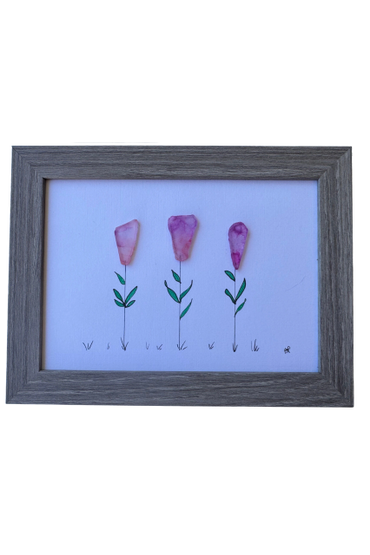 Framed art with pink sea glass flowers and hand-drawn green stems and leaves.