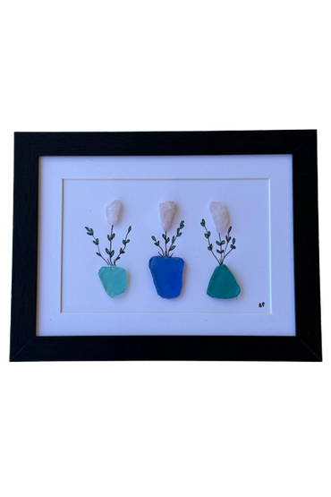 Framed art with three sea glass vases and rose quartz flowers.