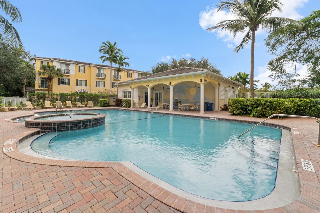 Outdoor pool with a hot tub, surrounded by palm trees