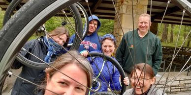 Six adults looking at the camera through the center of a bicycle wheel.