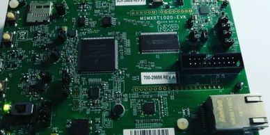 Close-up of a green printed circuit board with microchips and connectors.