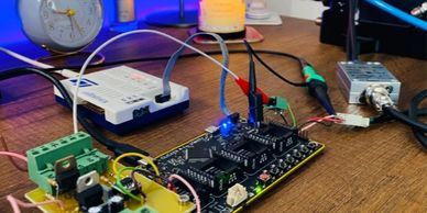 Electronic circuit board with connected wires and components on a wooden desk.