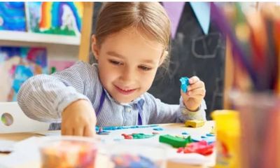 Young girl happily painting at a table.