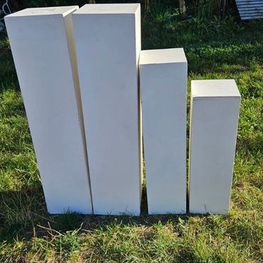 Four white rectangular pillars of varying heights standing on grass outdoors.