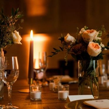 Elegant candlelit dining setup with flowers and glassware.