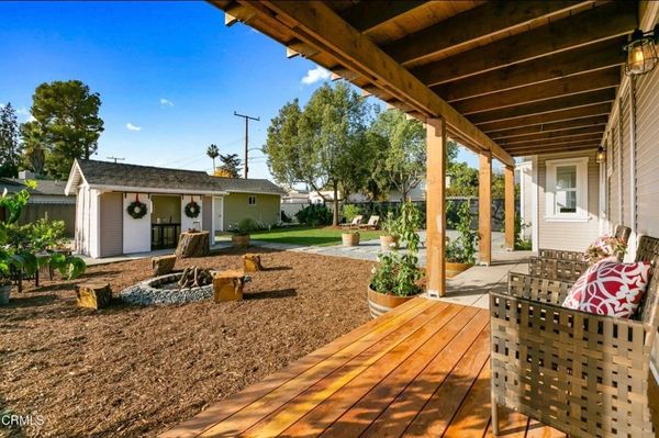 Cozy backyard with wooden deck, fire pit, and seating area under a covered porch.