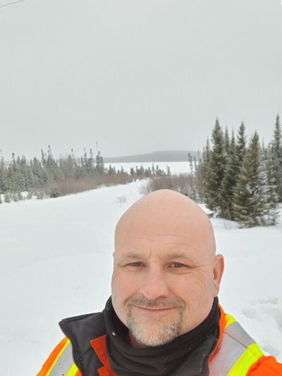 Smiling man in winter safety gear with snowy forest background.
